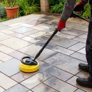 A person mopping a stone patio with an automatic brush