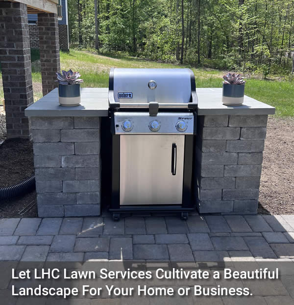 Image of a well constructed outdoor grill on a stone patio created by Let LHC Lawn Services With text: Let LHC Lawn Services Cultivate a Beautiful Landscape For Your Home or Business.
