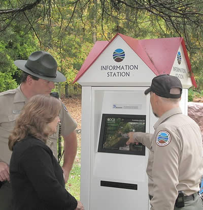three people standing at a state park kiosk